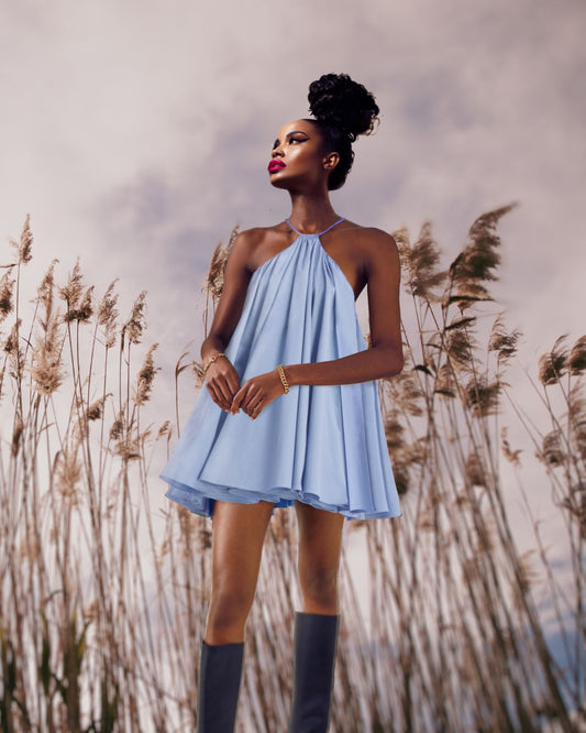 a young woman wearing a Maison Aria blue dress and posing in a wheat field 