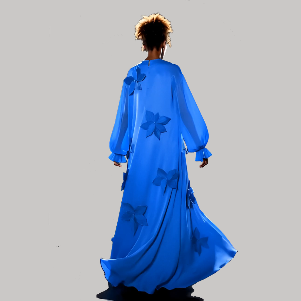 Person wearing a long blue dress with floral patterns on a gray background