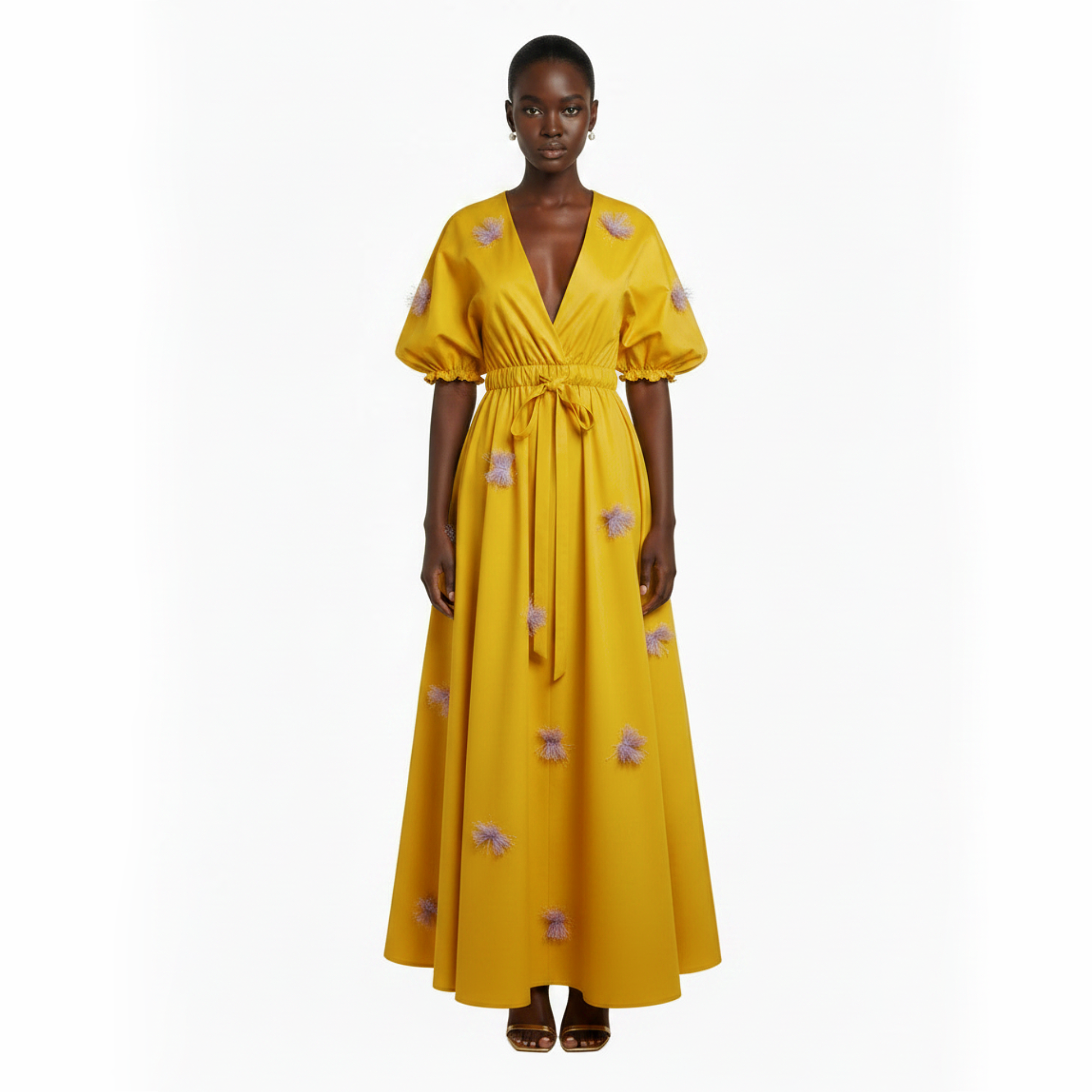 Woman wearing a yellow dress with floral patterns on a white background