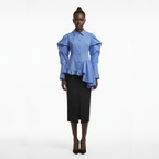 Woman wearing a blue peplum blouse and black skirt on a white background