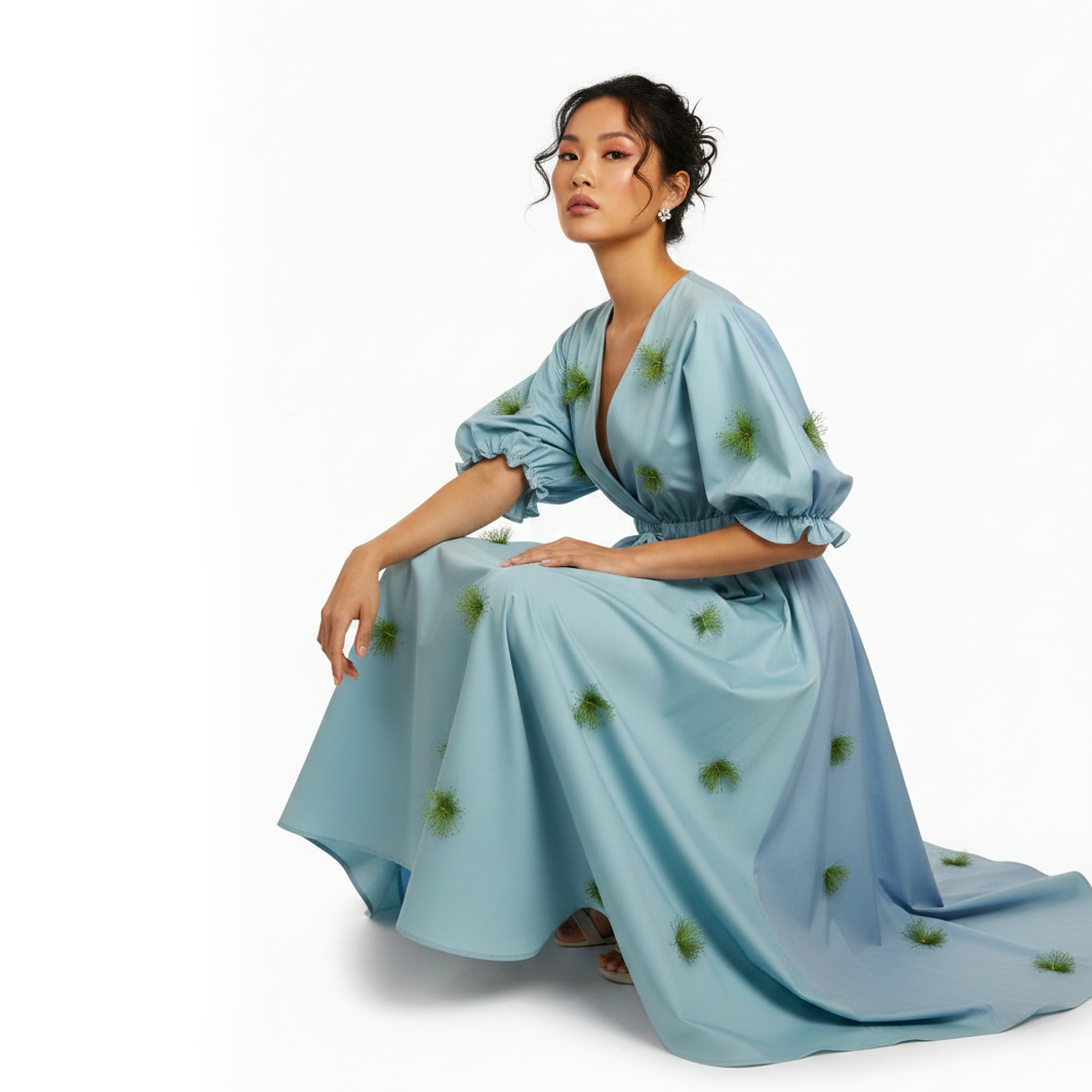 Woman wearing a light blue dress with green patterns on a white background