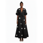 Black dress with white floral patterns worn by a model on a white background