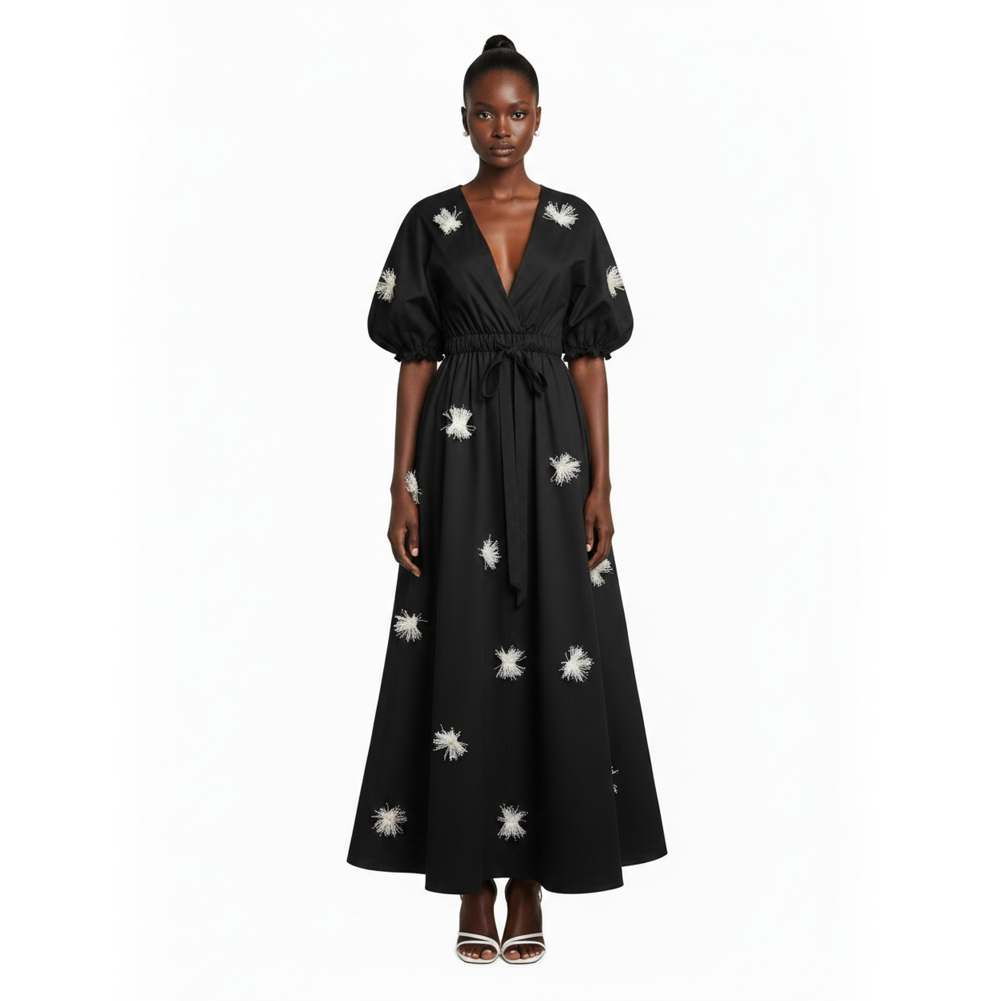 Black dress with white floral patterns worn by a model on a white background
