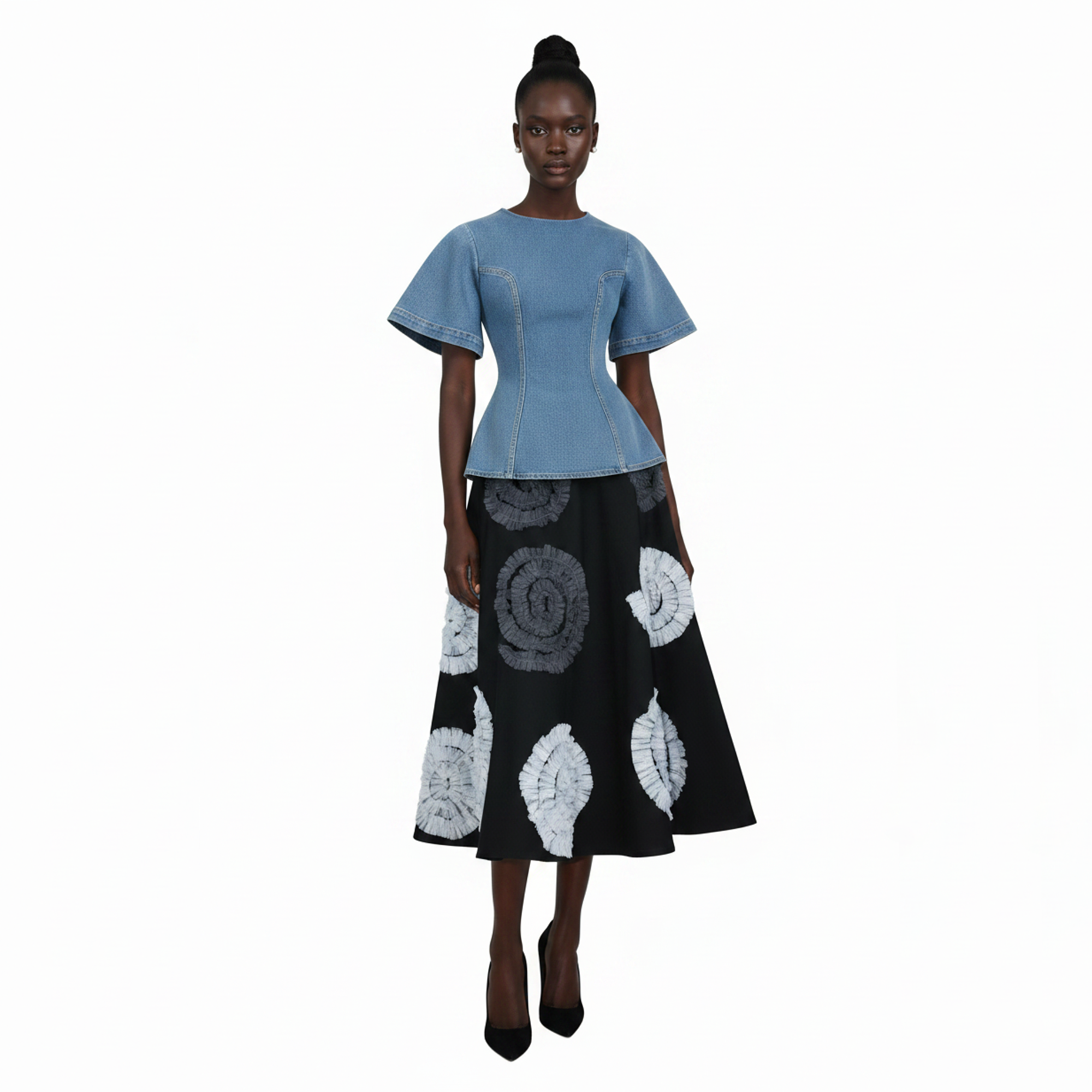 Woman wearing a blue top and black skirt with white patterns on a white background