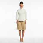 Woman wearing a white blouse and beige shorts on a white background