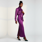 Woman wearing a purple outfit with a high slit on a white background