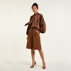 Woman wearing a brown satin blouse and skirt set on a white background