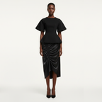 Black peplum top and ruched skirt worn by a model on a white background