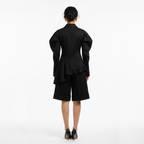 Person wearing a black outfit with a peplum top and shorts on a white background