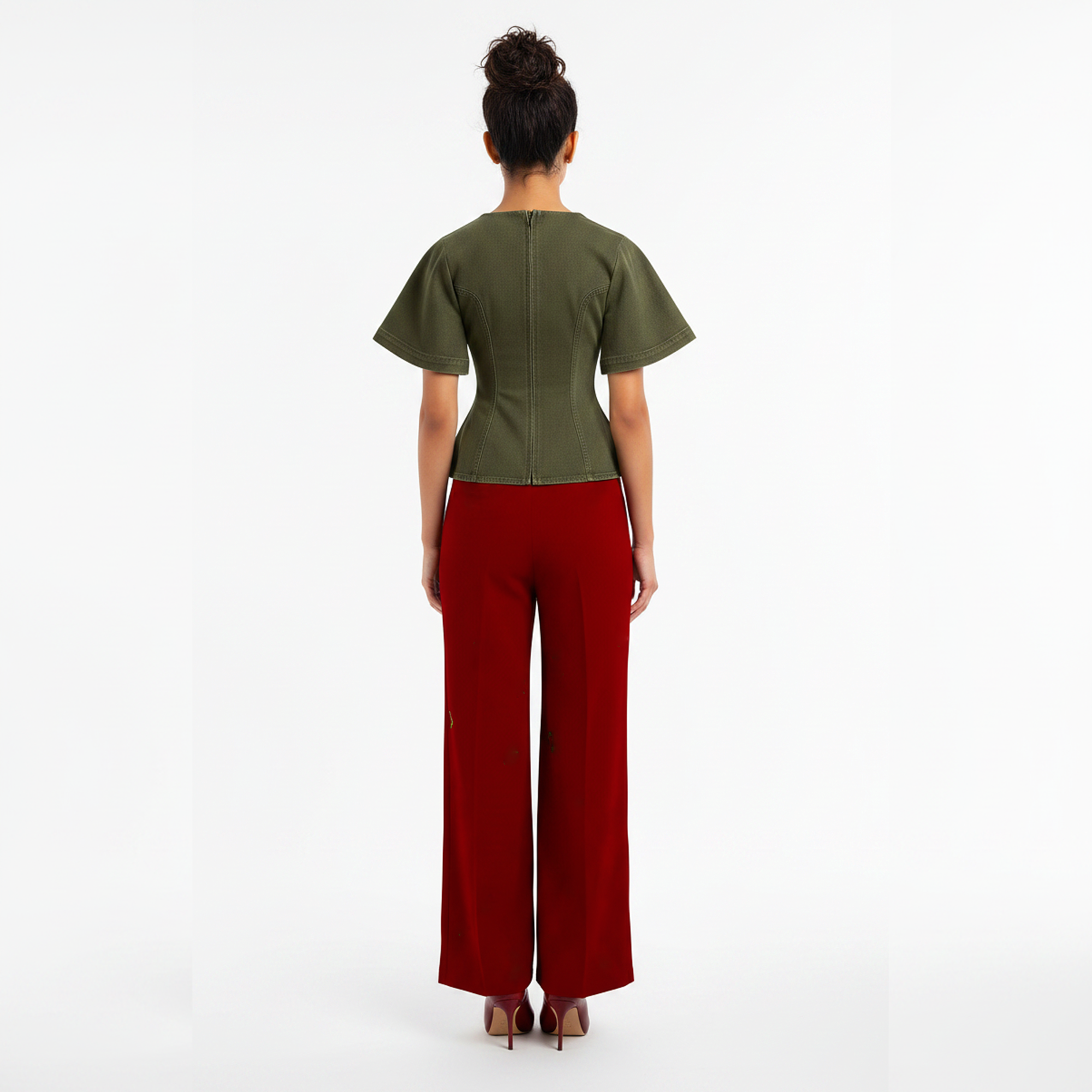 Woman wearing a green top and red pants on a white background