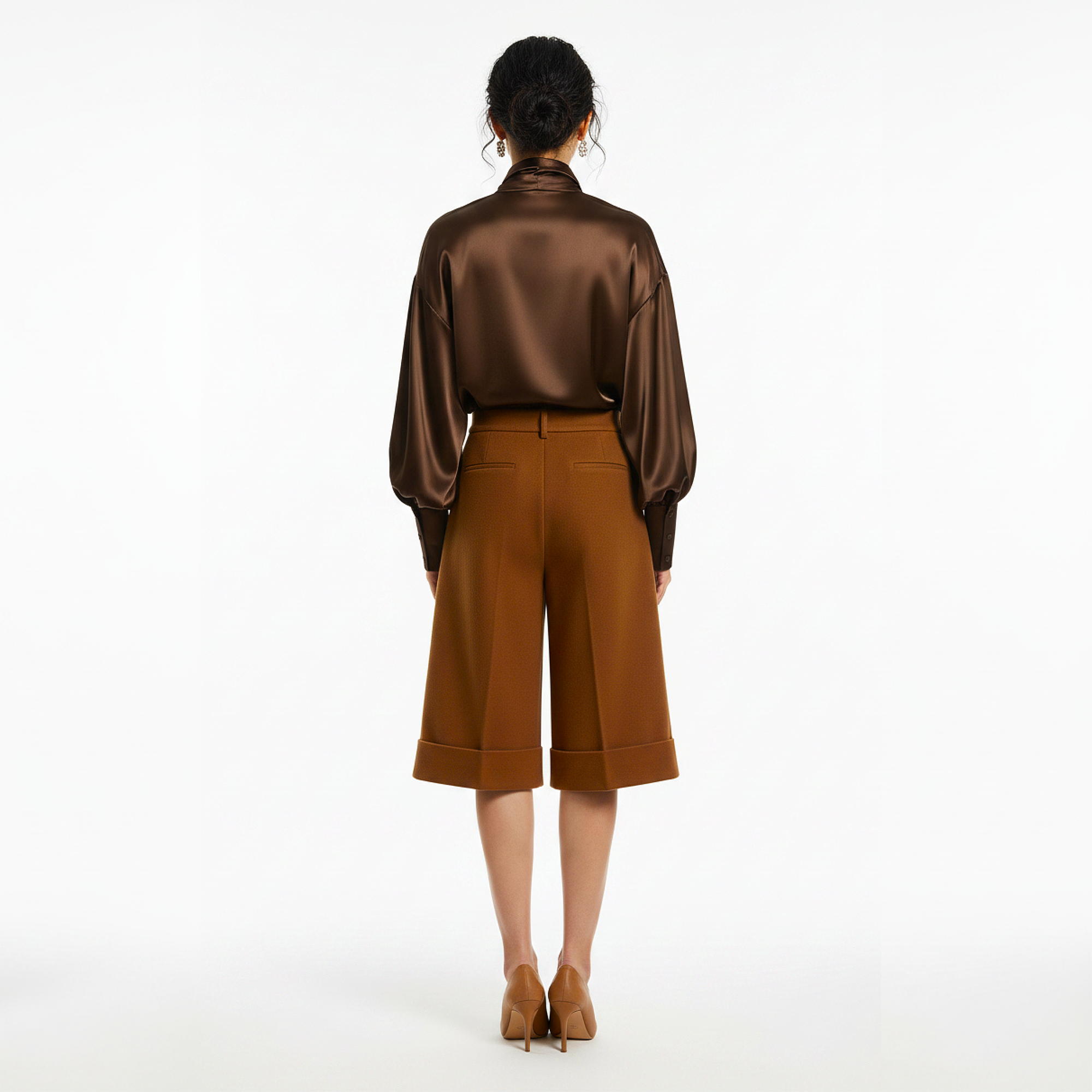 Person wearing a brown satin blouse and brown pants on a white background