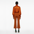 Person wearing a rust-colored satin outfit on a white background