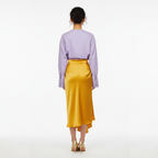 Person wearing a light purple shirt and yellow skirt on a white background