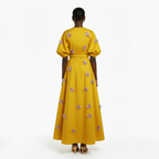 Woman wearing a yellow dress with floral patterns on a white background