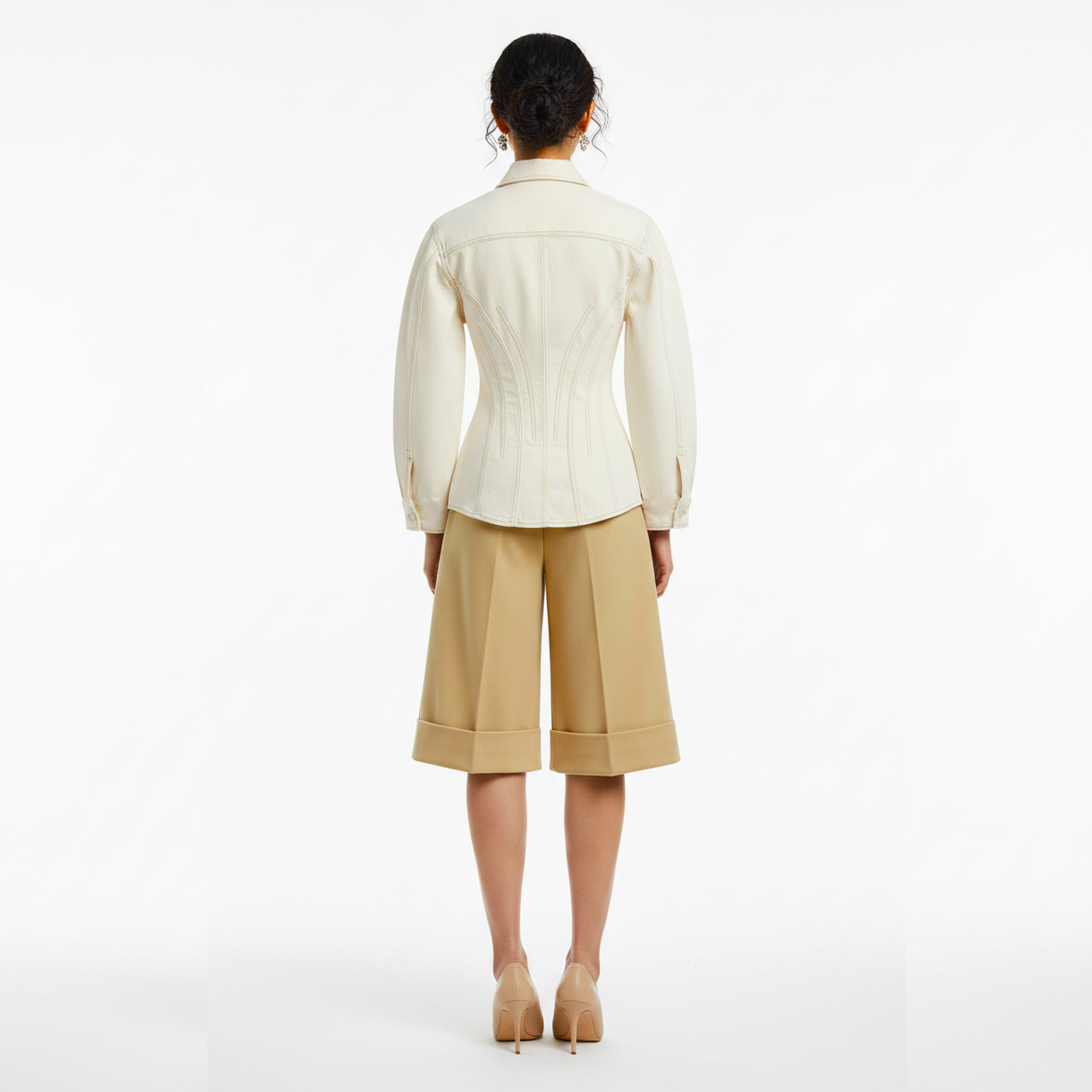 Woman wearing a cream blouse and beige pants on a white background