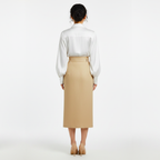 Person wearing a white blouse and beige skirt on a white background