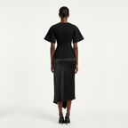 Person wearing a black dress with a belt on a white background