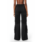 Black wide-leg pants with ruffled details on a white background