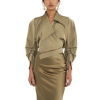 Woman wearing a beige outfit with a draped top and satin skirt on a white background