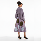 Woman wearing a purple dress with floral and geometric patterns on a white background