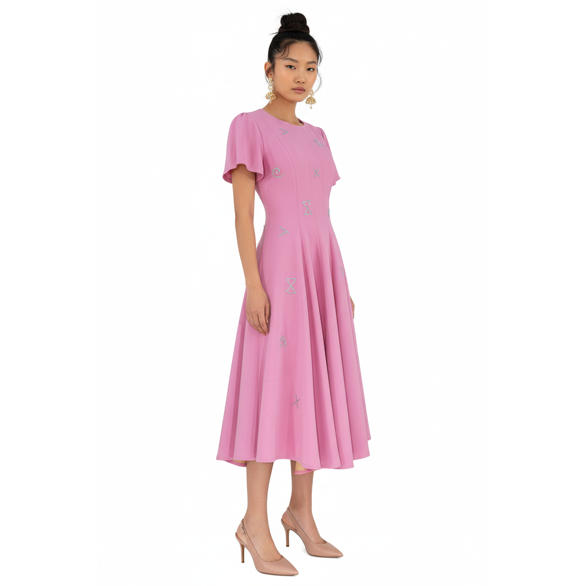 Woman wearing a pink dress with silver embellishments on a white background