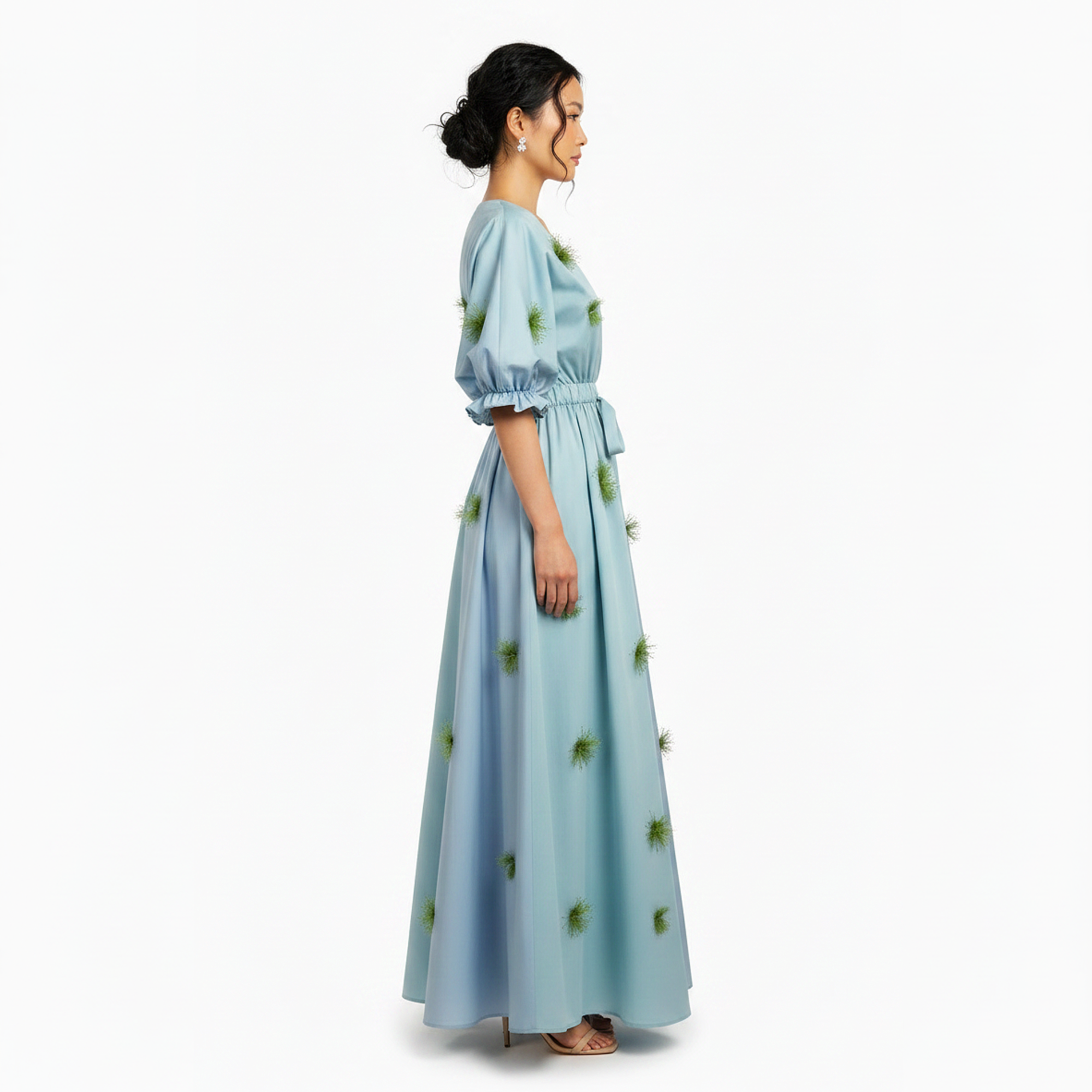 Woman wearing a light blue dress with pineapple pattern on a white background