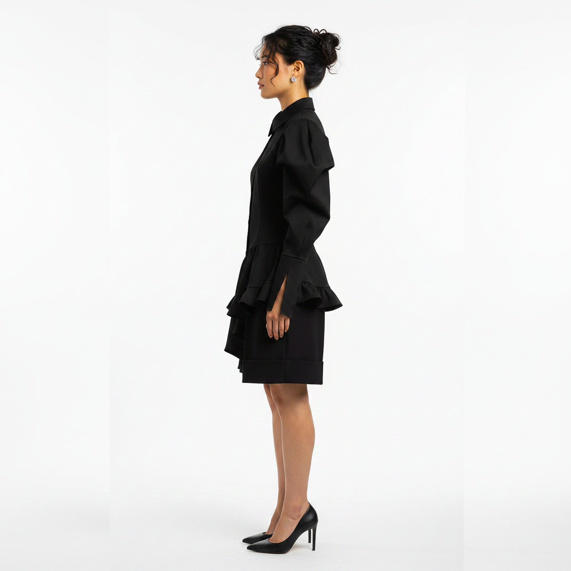 Woman wearing a black outfit with ruffled details on a white background