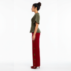 Woman wearing a green top and red pants with green patterns on a white background