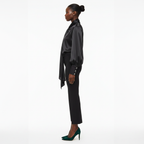 Woman wearing a black satin blouse and black pants on a white background