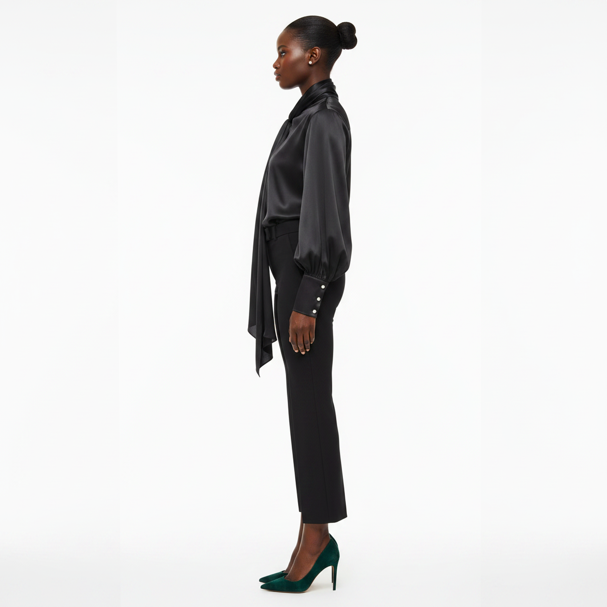 Woman wearing a black satin blouse and black pants on a white background