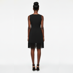 Woman wearing a black dress with sheer lace trim on a white background