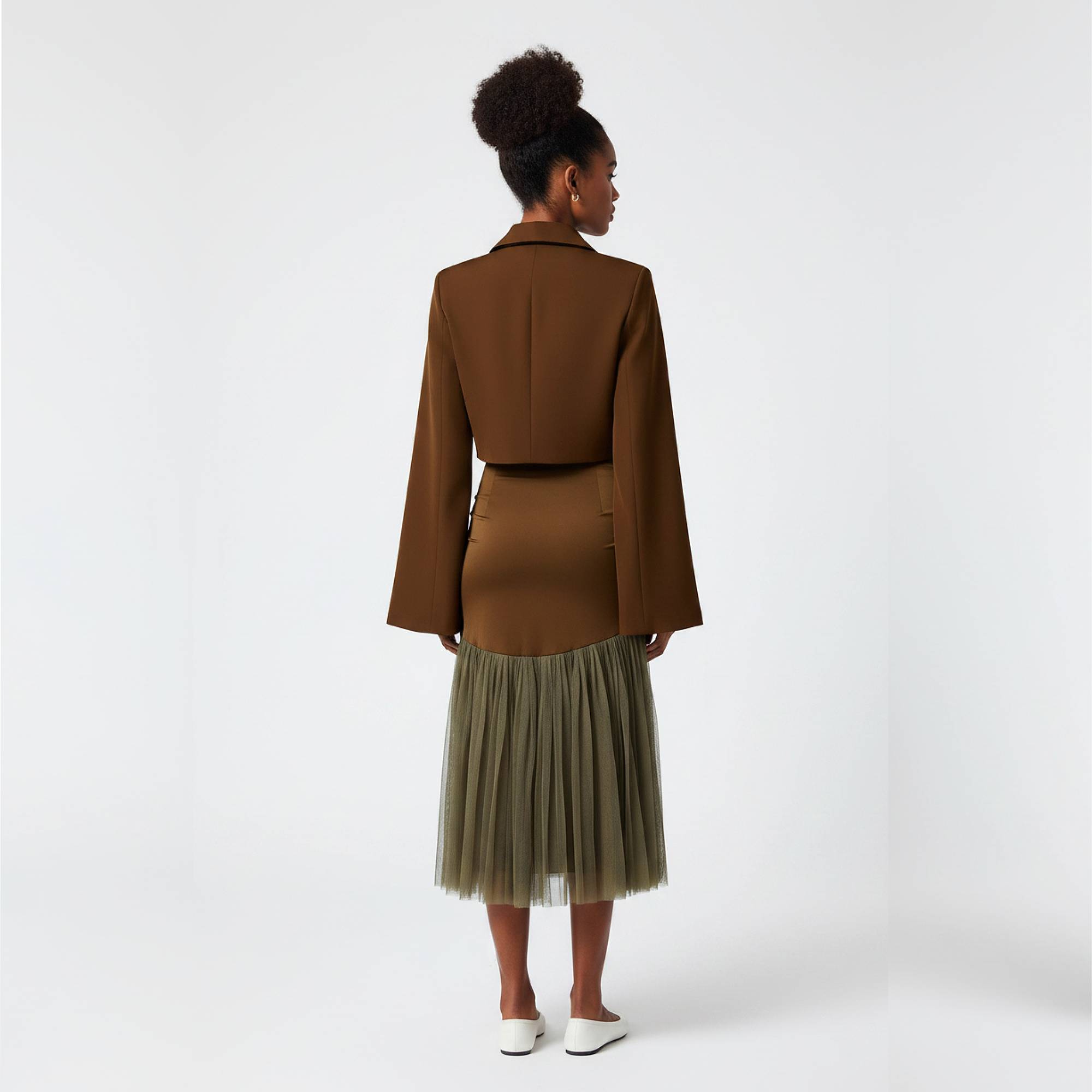 Woman wearing a brown jacket and skirt with a beige tulle hem on a white background