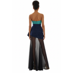 Woman wearing a strapless teal top and navy blue dress with sheer black panels on a white background