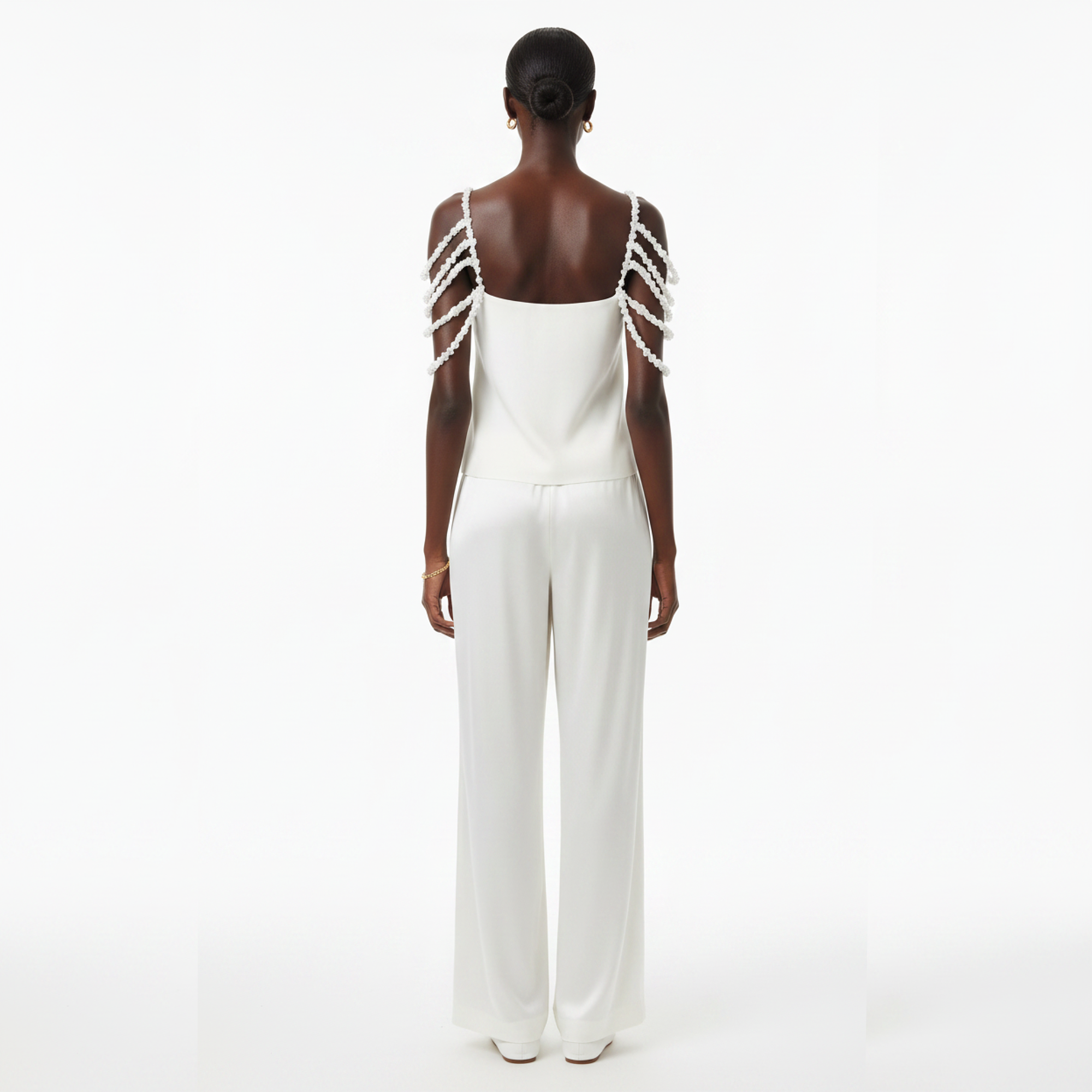 A person wearing a white top with pearl shoulder straps on a white background