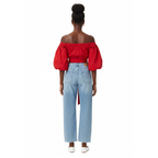 Woman wearing a red off-shoulder top with a blue jeans on a white background