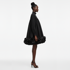 Woman wearing a black dress with ruffled skirt on a white background
