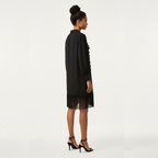 Woman wearing a black dress with sheer overlay on a white background