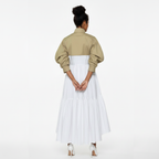 Woman wearing a beige jacket over a white dress on a white background