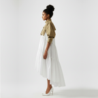 Woman wearing a beige shirt and white skirt on a plain background