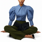 Woman sitting cross-legged wearing a blue blouse and green pants on a white background