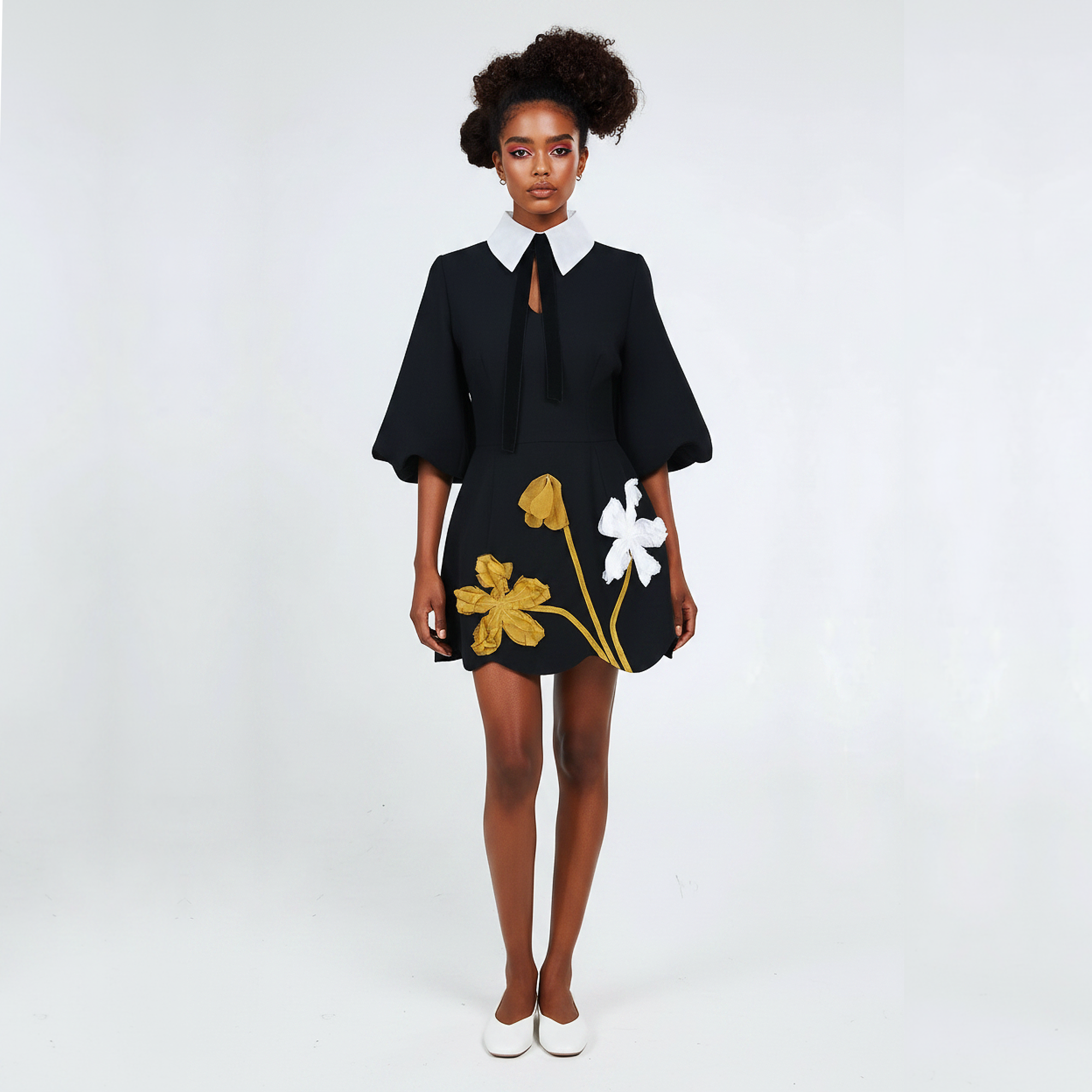 Woman wearing a black dress with floral designs on a white background