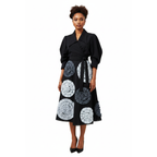 Woman wearing a black coat with a patterned skirt on a white background