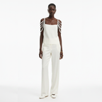 A person wearing a white top with pearl shoulder straps on a white background