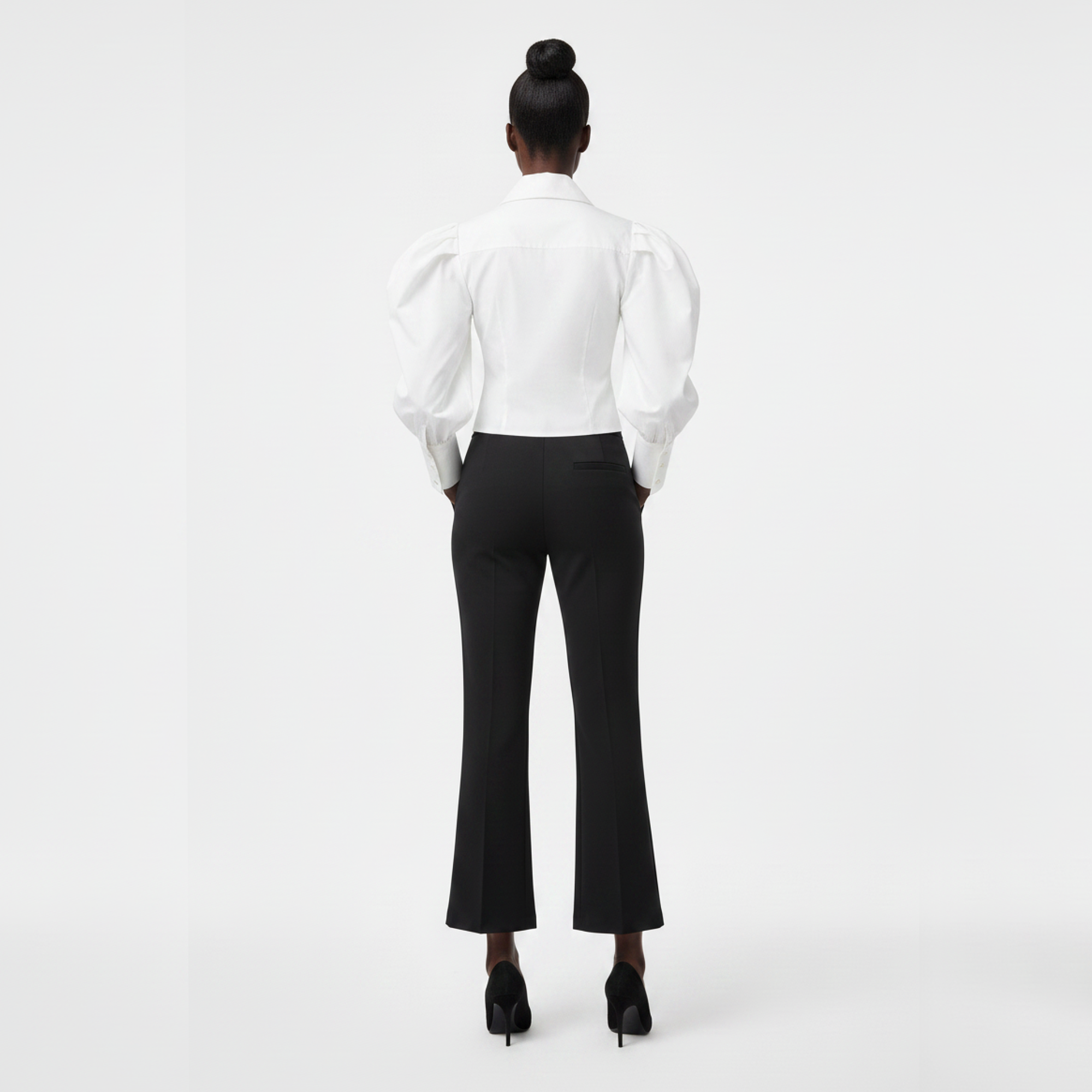 Person wearing a white blouse and black pants on a white background