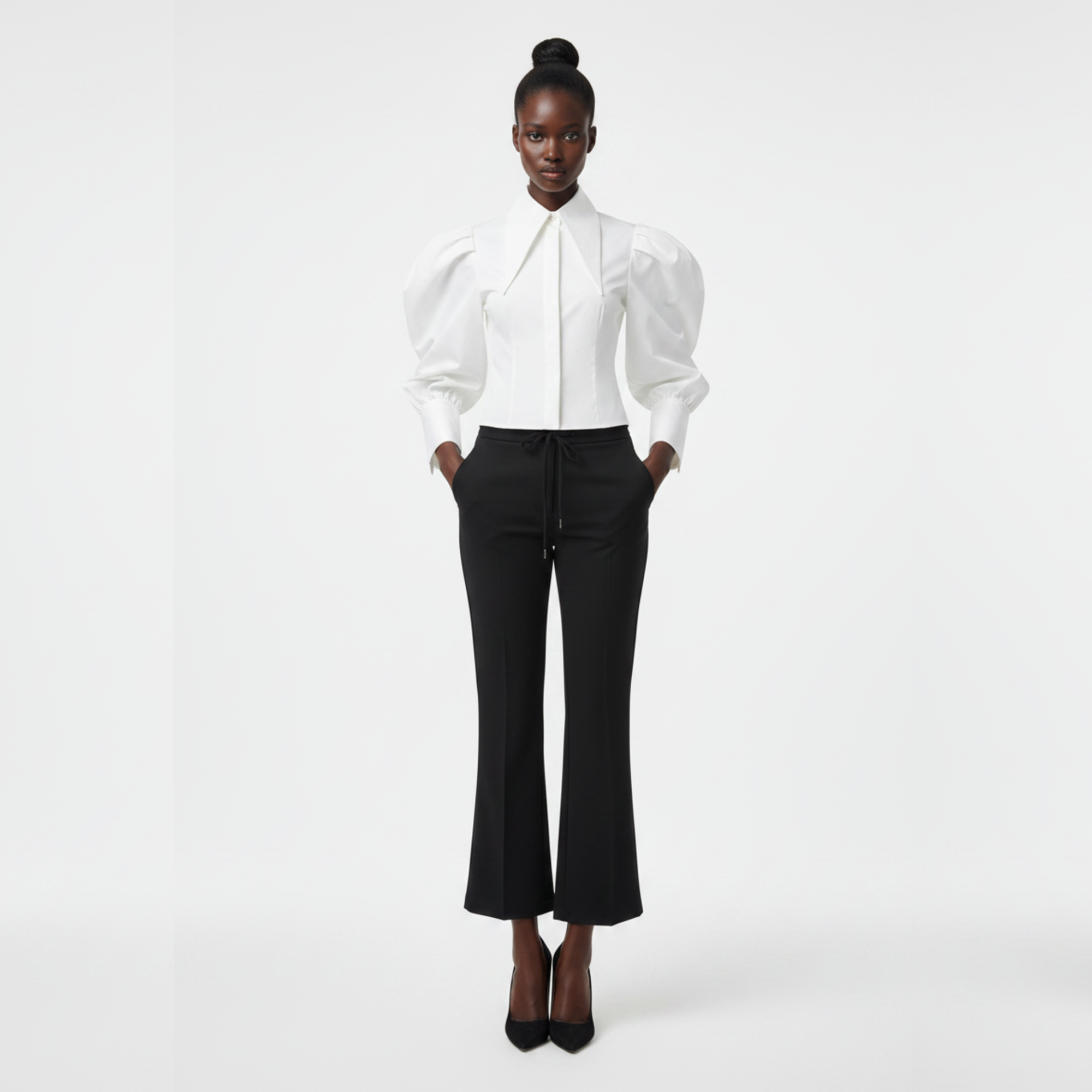 Person wearing a white blouse and black pants on a white background