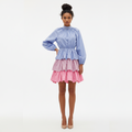 Woman wearing a two-tone dress with a blue top and pink skirt on a white background