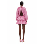 Pink dress with a bow detail on the back worn by a model on a white background