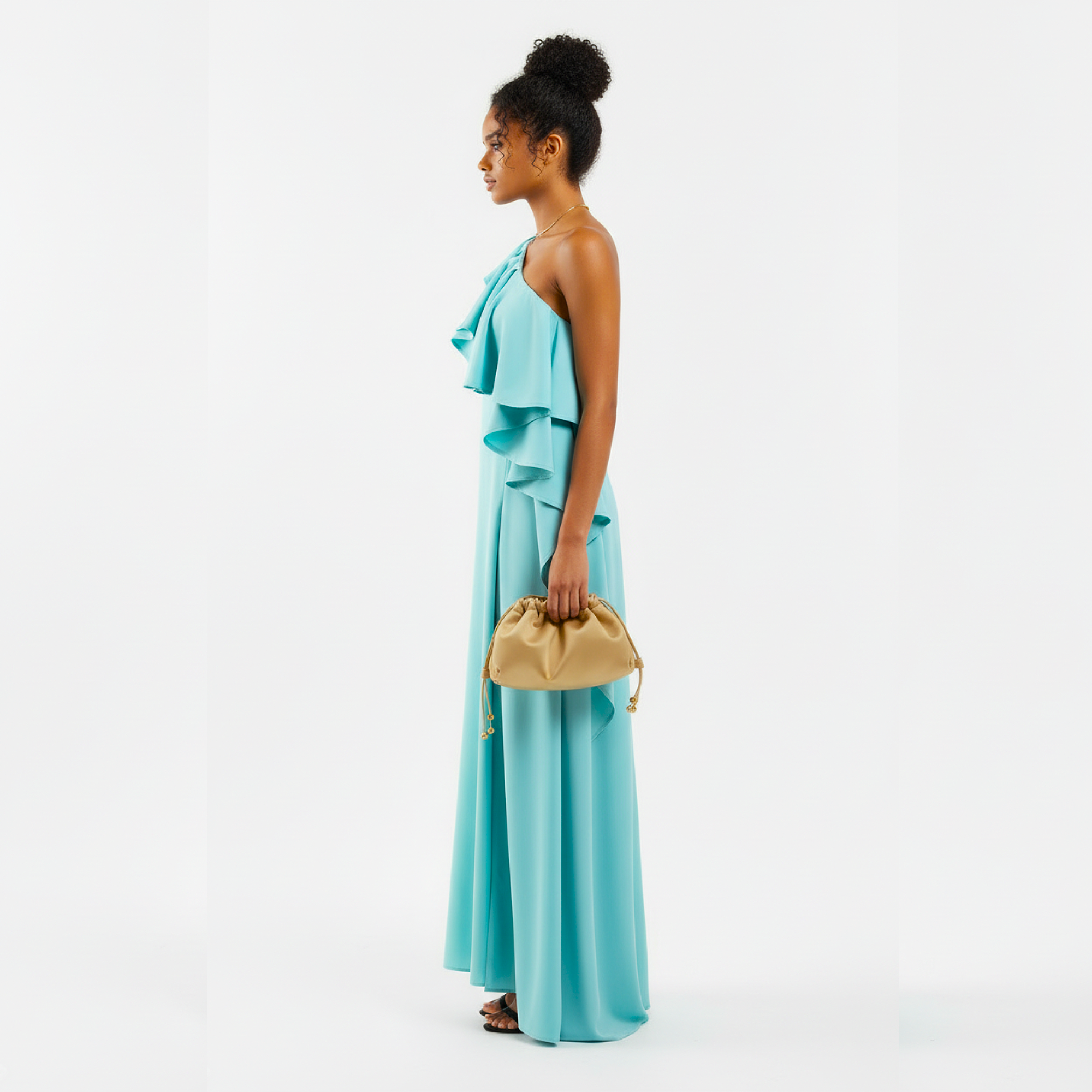 Woman wearing a turquoise dress holding a gold clutch against a white background
