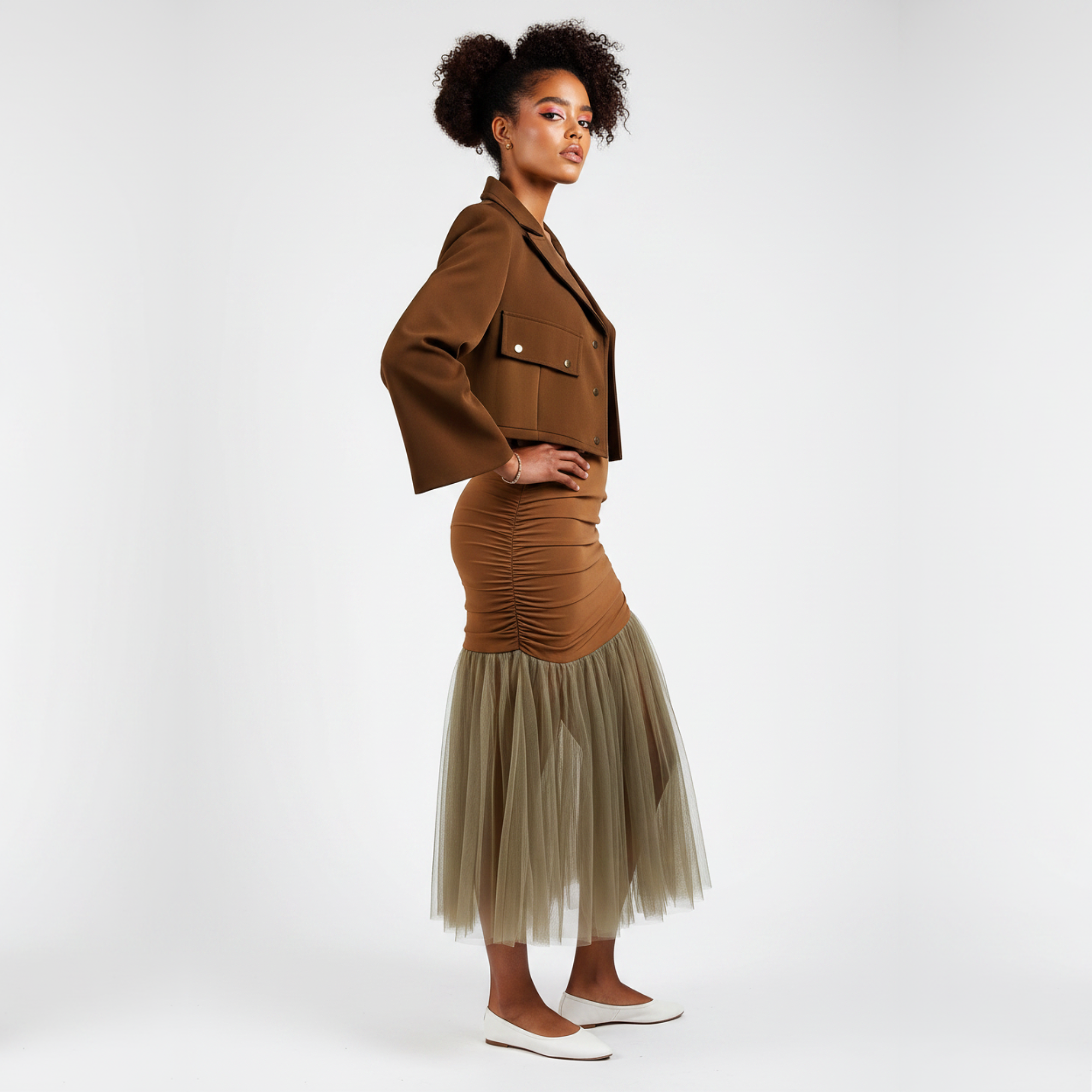 Woman wearing a brown jacket and skirt with a beige tulle hem on a white background